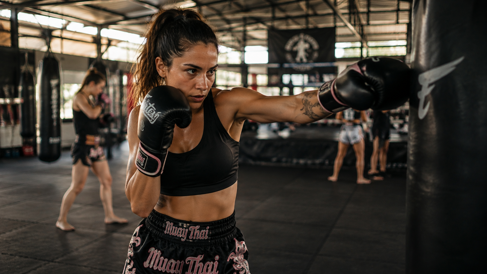 Praticante de muay thai feminino treinando golpes com foco e presença no tatame